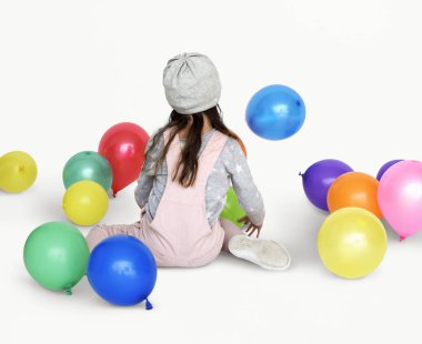 Balonlarla oturan küçük kız