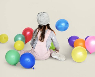 Balonlarla oturan küçük kız
