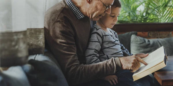 Дедушка читает книгу с внуком — стоковое фото
