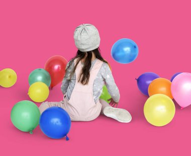 Balonlarla oturan küçük kız