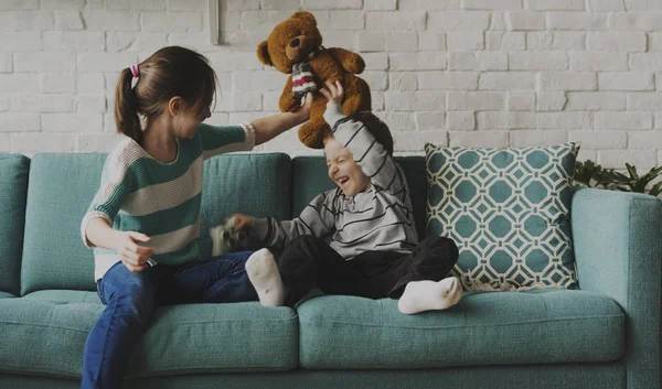 Bror och syster spelar på soffa — Stockfoto