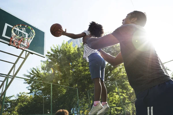 girl playing basketball with father