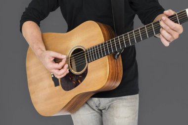 Adam akustik gitar çalıyor.