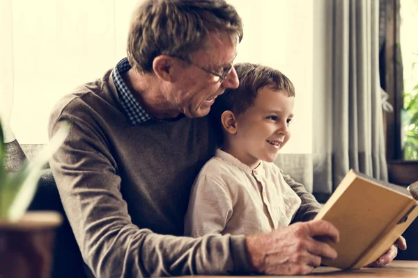 Дедушка читает книгу с внуком — стоковое фото