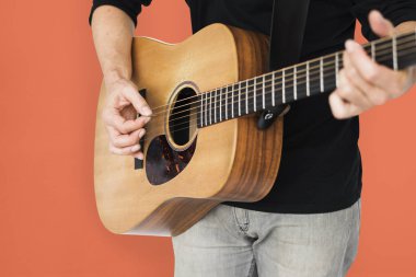 Adam akustik gitar çalıyor.