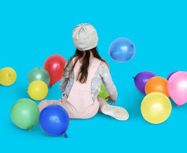 Balonlarla oturan küçük kız