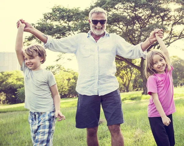 Счастливого дедушки, гуляющего с внуками — стоковое фото