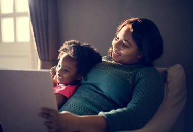 Anne ve kızı kitap okuyor.