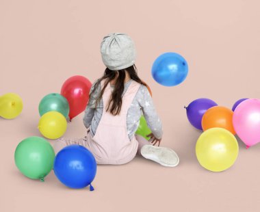 Balonlarla oturan küçük kız