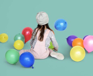 Balonlarla oturan küçük kız