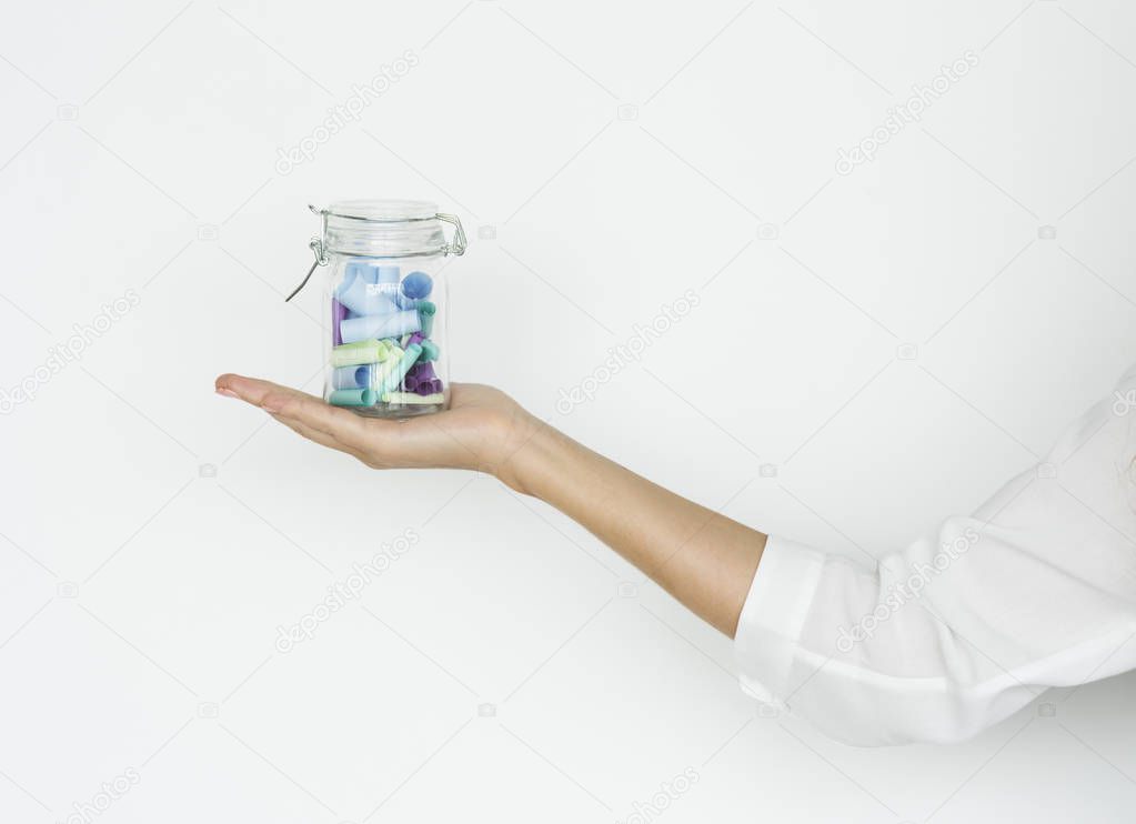 Hand holding jar with paper scrolls