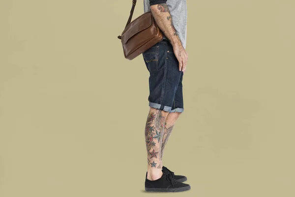 Чоловік з сумкою та татуюваннями на нозі — стокове фото