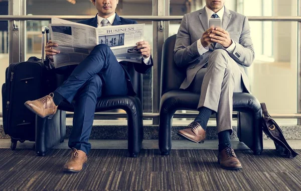 Des hommes d'affaires lisant des journaux et utilisant un smartphone — Photo