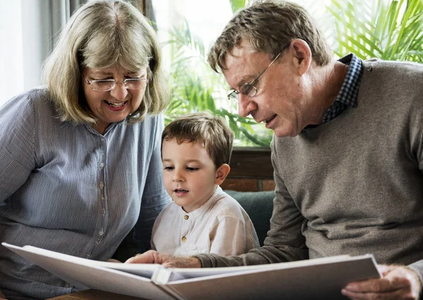 grandparents and grandson reading book