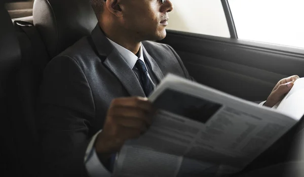 Empresario leyendo periódico dentro del coche — Foto de Stock