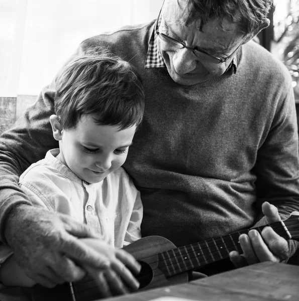 Дедушка и внук играют на укулеле — стоковое фото