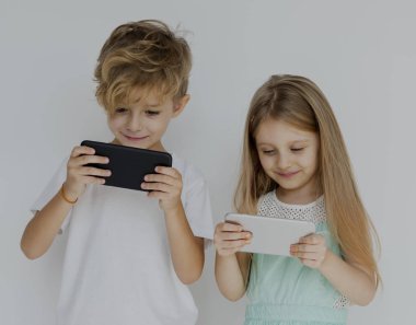 Akıllı telefonlar üzerinde oynayan çocuklar