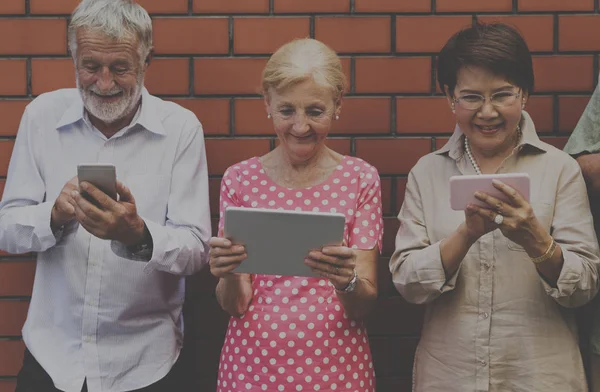 Anziani che navigano dispositivi digitali — Foto Stock