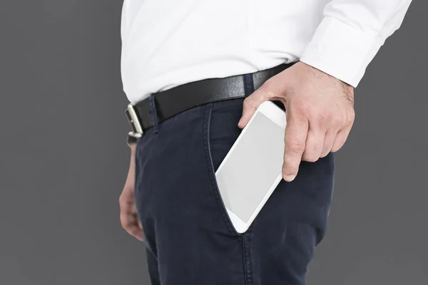 Бизнесмен кладет смартфон в карман — стоковое фото