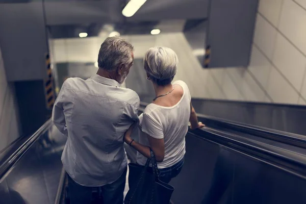 Starší turisté na eskalátoru na letišti — Stock fotografie