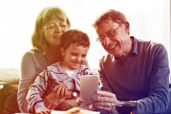 Avós e neto usando smartphone — Fotografia de Stock