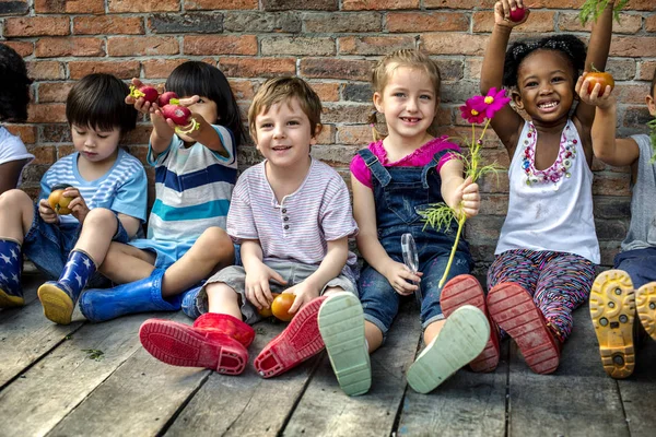 Група дітей дитячого садка, що сидять біля цегляної стіни — стокове фото