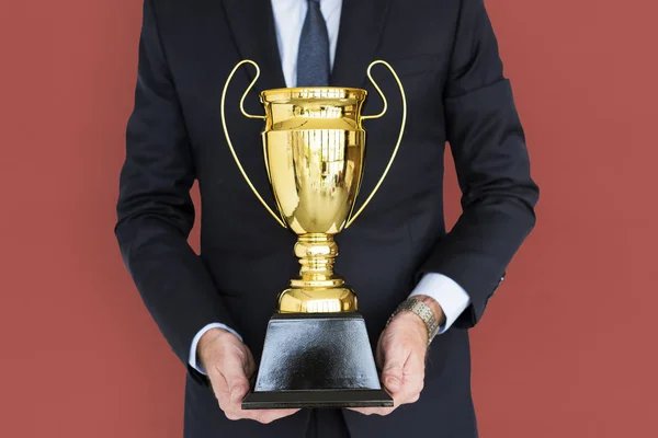 Empresário segurando troféu dourado — Fotografia de Stock