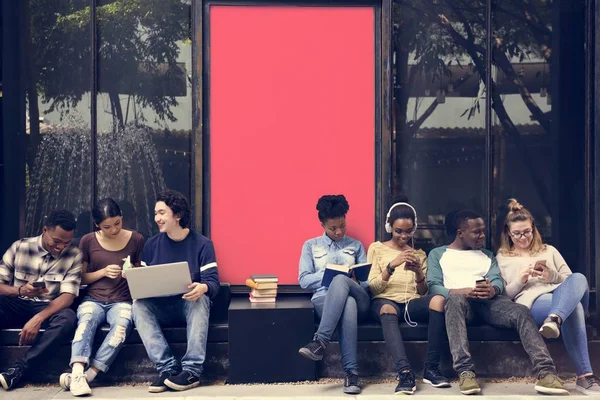 Jeunes étudiants assis près d'une pancarte — Photo