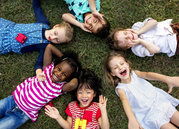 Kleuterschool kinderen liggen op gras in het park — Stockfoto