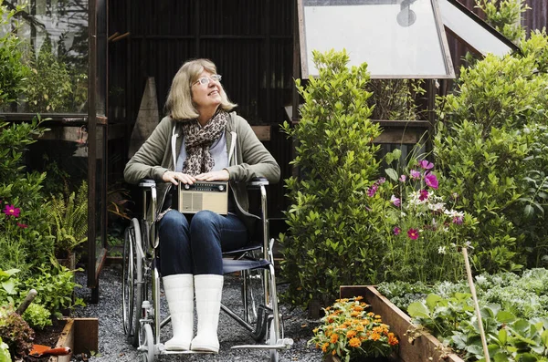 Kobieta na wózku inwalidzkim w ogrodzie — Zdjęcie stockowe