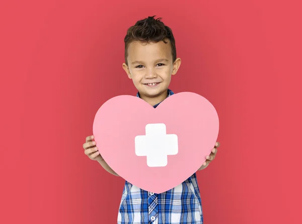 Menino segurando coração com cruz — Fotografia de Stock