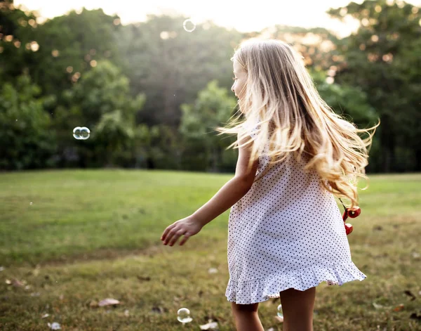 Девушка играет с пузырьками в парке — стоковое фото