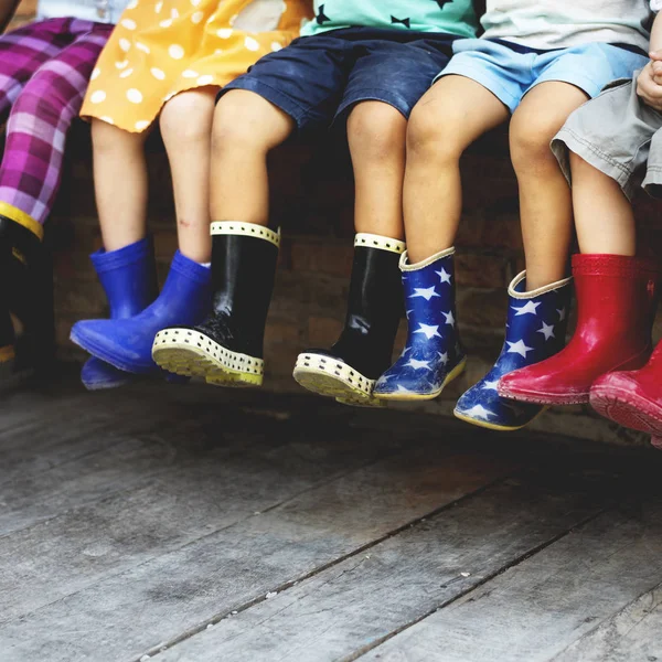 Діти сидіти разом в гумові чоботи — стокове фото