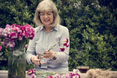 Olgun Bayan çiçek düzenliyor