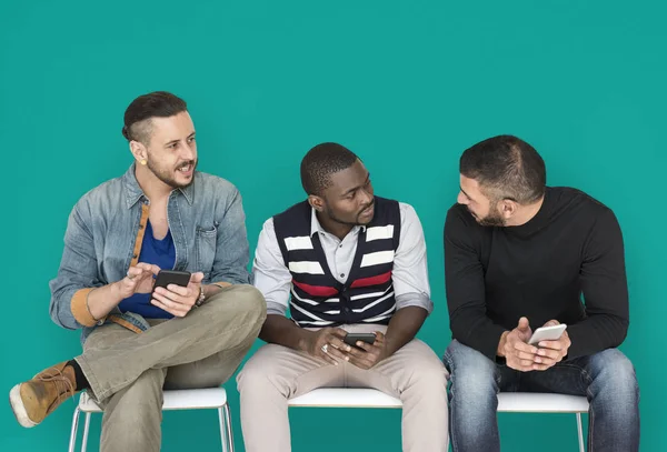 Manliga vänner sitter på bänken med smartphones — Stockfoto