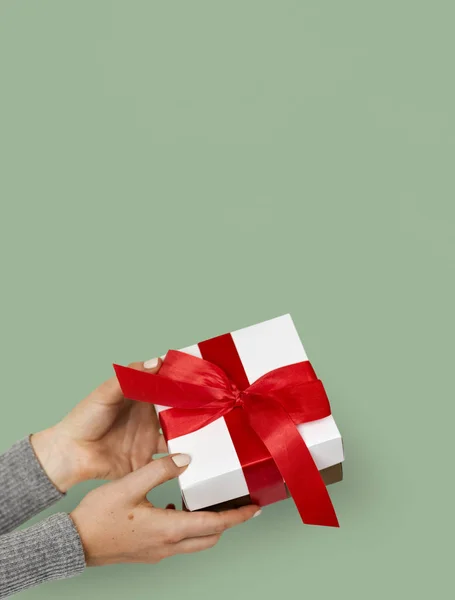 Segurando caixa de presente com arco vermelho — Fotografia de Stock
