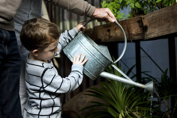 Grands-parents et petits-fils arrosage des plantes — Photo