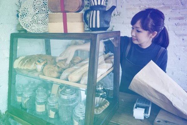 Mulher colocando massa de pão na prateleira — Fotografia de Stock