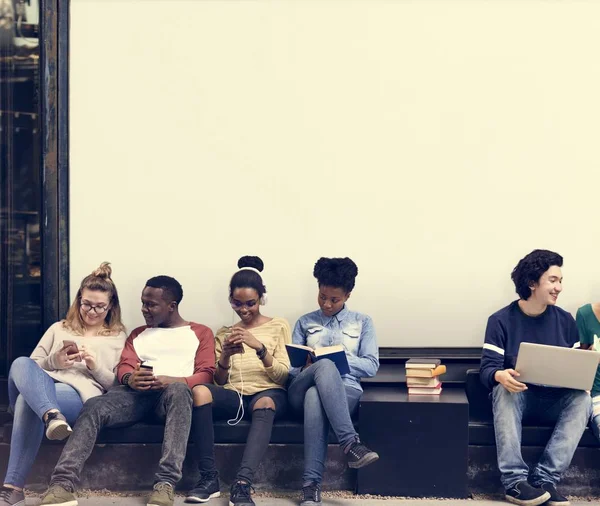 Jeunes étudiants assis près d'une pancarte — Photo