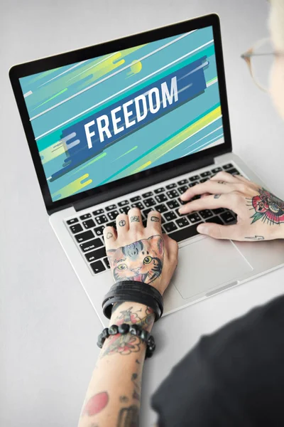 Tattooed person typing on laptop. — Stock Photo, Image