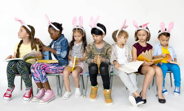 Niños en diademas de conejo estudiando con libros —  Fotos de Stock
