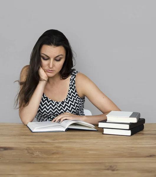 Frau liest Bücher, während sie am Tisch sitzt — Stockfoto