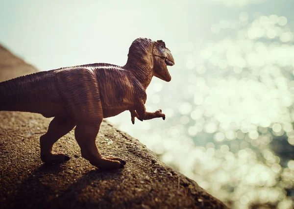 Dinosaur figure toy outdoors near sea water, original photoset