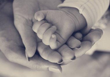 Yeni doğan bebeğin elini tutarak anne