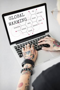 Dövmeli kişi dizüstü bilgisayarda yazarak.