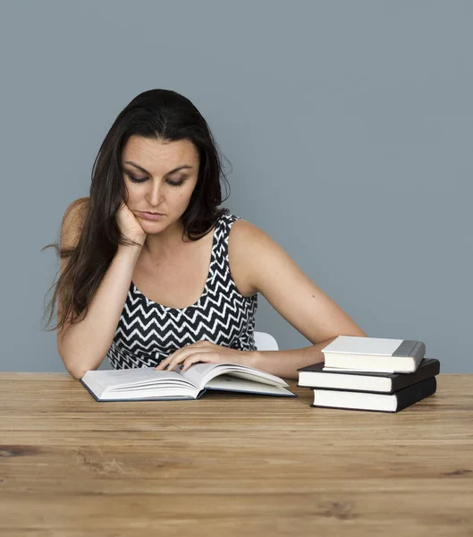 Frau liest Bücher, während sie am Tisch sitzt — Stockfoto