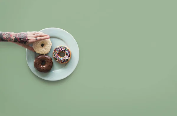 Mano y rosquillas en el plato — Foto de Stock