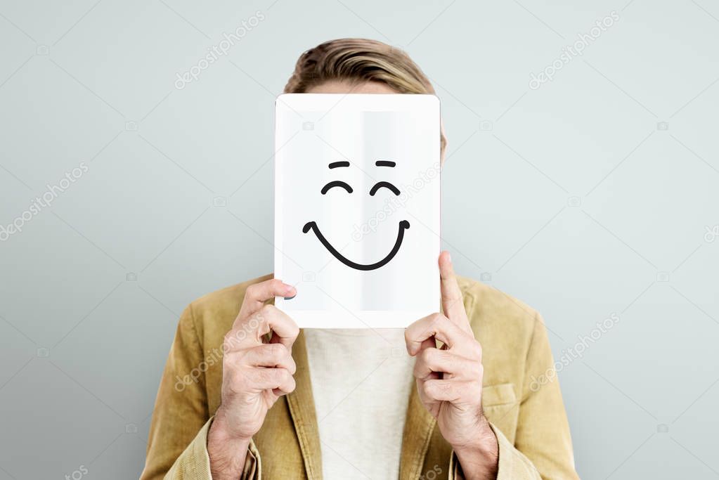 man holding digital tablet covering face
