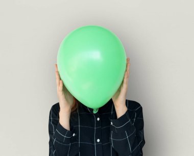 Yeşil balon ile yüz kapsayan kadın