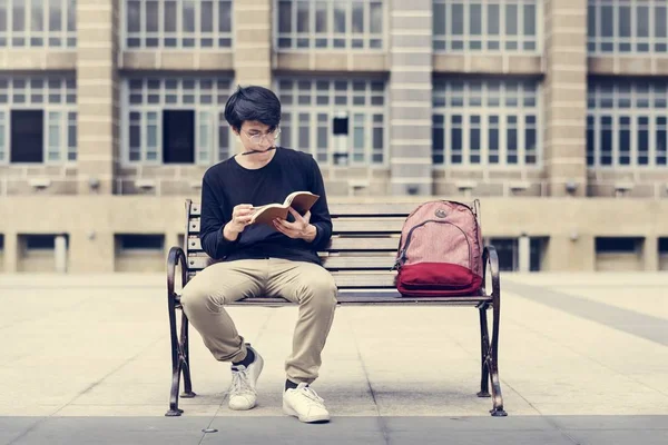 Estudiante sentado en el banco y la celebración de cuaderno —  Fotos de Stock